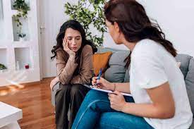 A client sharing how she feels while a therapist listens and takes notes
