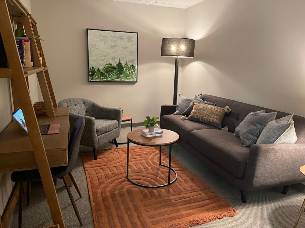 The therapy office — a cozy room with a couch, armchair, and warm lamplight